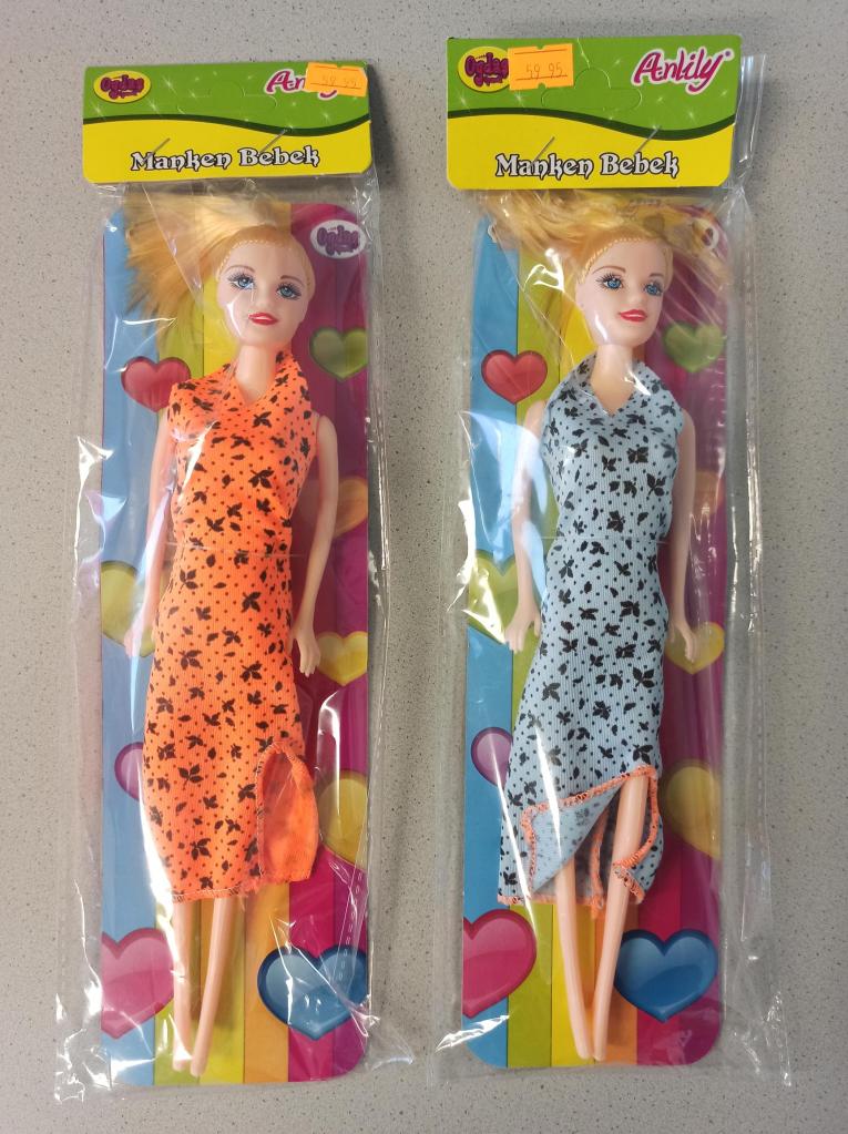 Das Foto zeigt zwei Puppen mit blonden Haaren, eine in einem orangenen und eine in einem blauen Kleid. Die Verpackungen sind grün-gelb mit bunten Herzen darauf.
